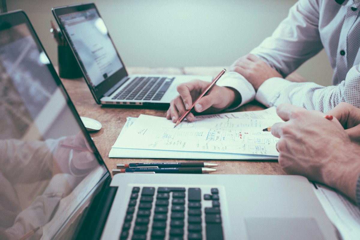 Editorial analyst reviewing digital documentation, checklists, and source verification materials on modern laptop